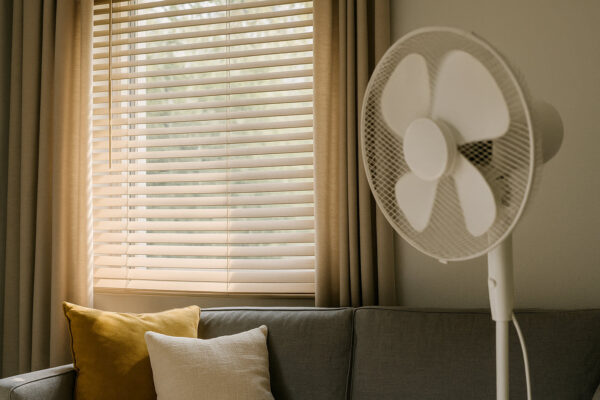 Sommerliches Wohnzimmer mit geschlossenen Jalousien und Ventilator für angenehmes Raumklima